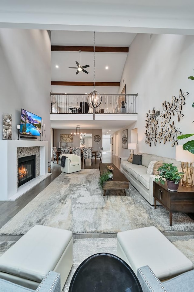 living room featuring beamed ceiling, ceiling fan with notable chandelier, and high vaulted ceiling