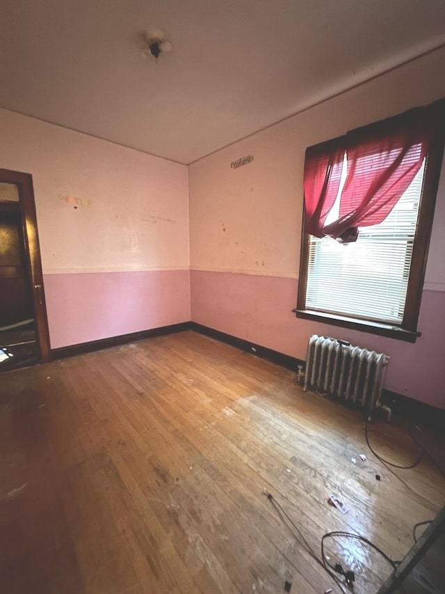 spare room featuring radiator heating unit and wood-type flooring