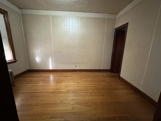 empty room with crown molding and light wood-type flooring