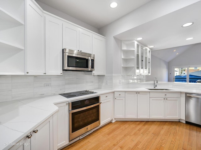 kitchen with sink, light stone counters, backsplash, white cabinets, and appliances with stainless steel finishes