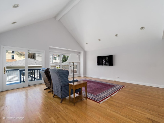 living room with beamed ceiling, light hardwood / wood-style floors, and high vaulted ceiling