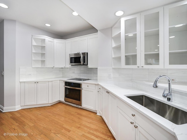 kitchen with white cabinets, appliances with stainless steel finishes, light hardwood / wood-style floors, and sink