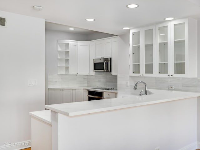 kitchen featuring white cabinets, oven, cooktop, and kitchen peninsula