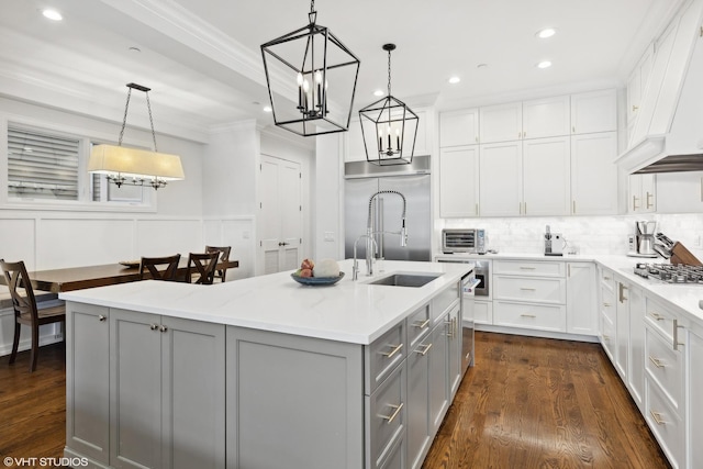 kitchen featuring gray cabinetry, a center island with sink, hanging light fixtures, light stone countertops, and stainless steel appliances