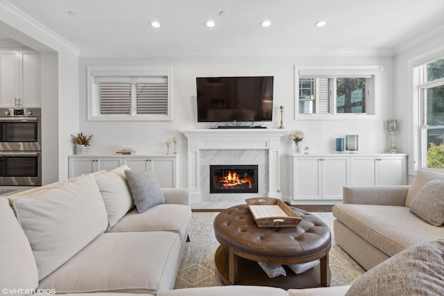 living room featuring a high end fireplace, a wealth of natural light, and crown molding