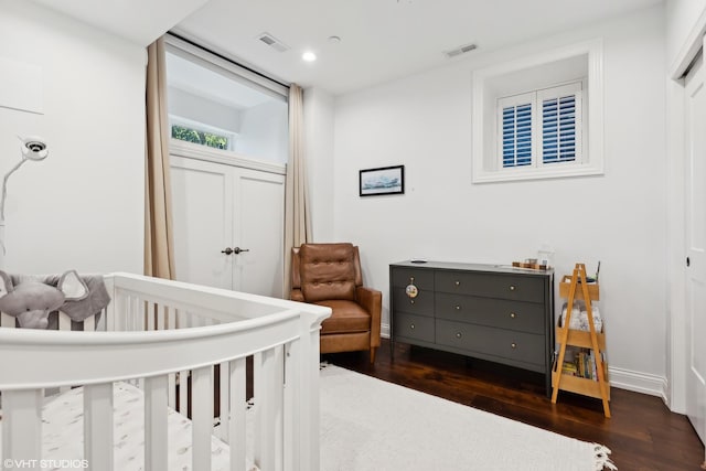 bedroom with dark hardwood / wood-style flooring, a crib, and a closet