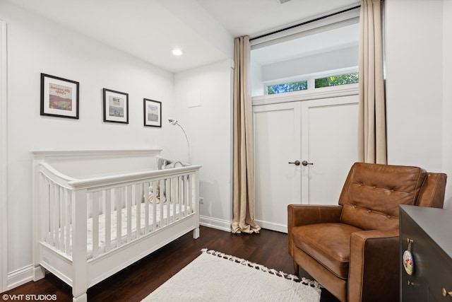 bedroom featuring a nursery area and dark wood-type flooring