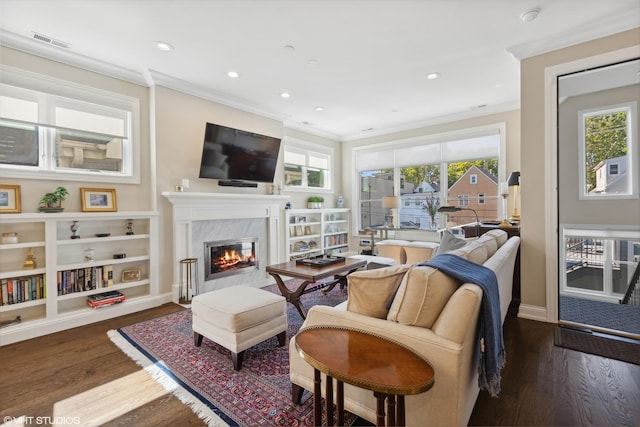 living room featuring a high end fireplace, ornamental molding, a wealth of natural light, and dark wood-type flooring