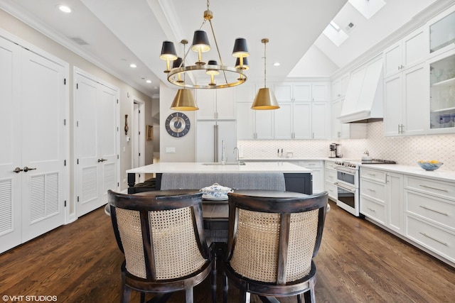 kitchen featuring decorative backsplash, a skylight, custom exhaust hood, range with two ovens, and white cabinets