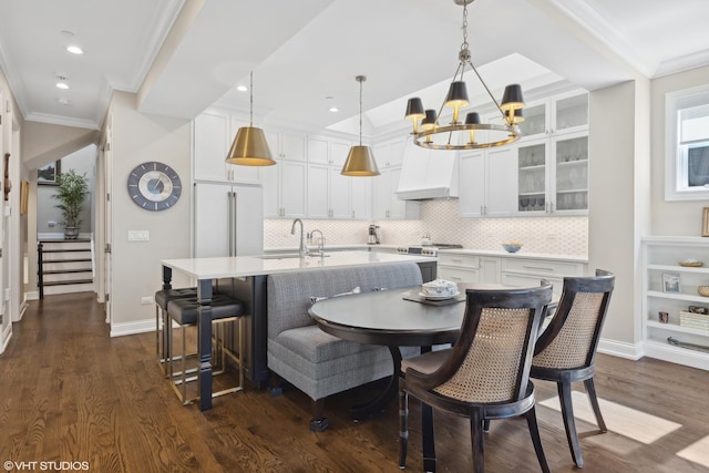 dining room with dark hardwood / wood-style floors, ornamental molding, sink, and an inviting chandelier