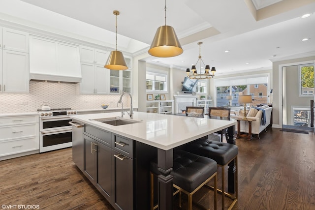 kitchen featuring a raised ceiling, sink, decorative light fixtures, white cabinets, and stainless steel stove