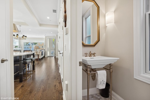 bathroom with hardwood / wood-style flooring, an inviting chandelier, and ornamental molding