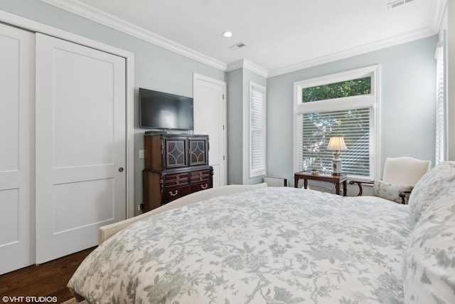 bedroom with dark hardwood / wood-style flooring, crown molding, and a closet