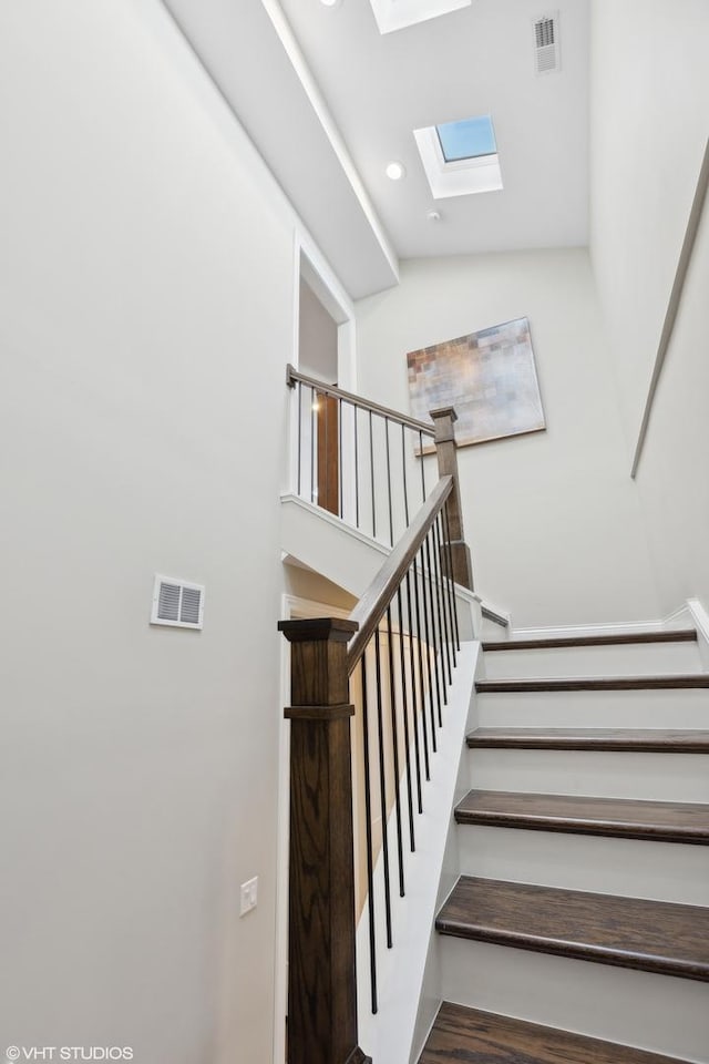 stairway with hardwood / wood-style floors and lofted ceiling with skylight