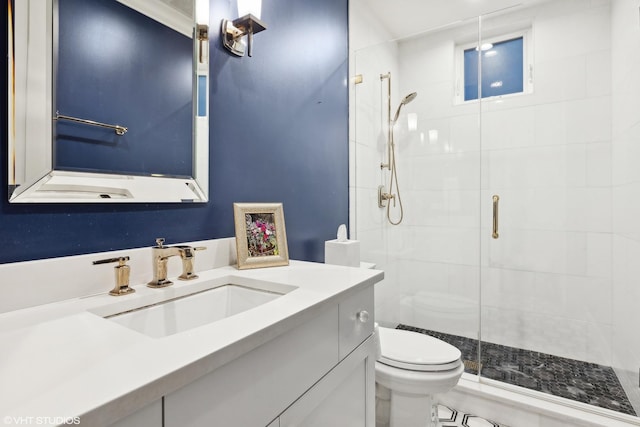 bathroom featuring a shower with door, vanity, and toilet