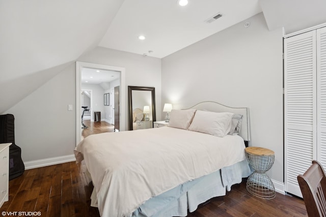 bedroom with vaulted ceiling, dark wood-type flooring, and a closet