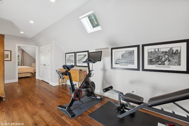 exercise room with wood-type flooring and lofted ceiling with skylight