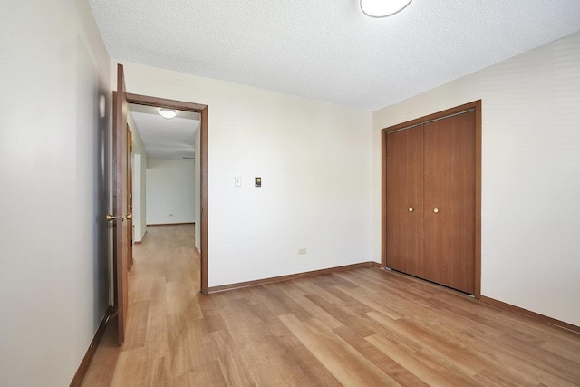 unfurnished bedroom with light wood-type flooring, a textured ceiling, and a closet