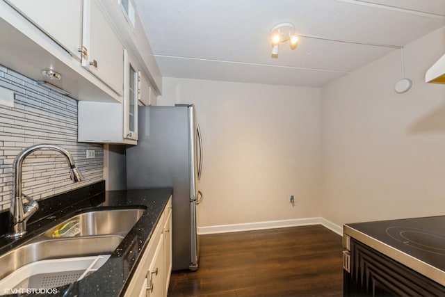 kitchen featuring dark hardwood / wood-style floors, tasteful backsplash, white cabinetry, dark stone counters, and sink