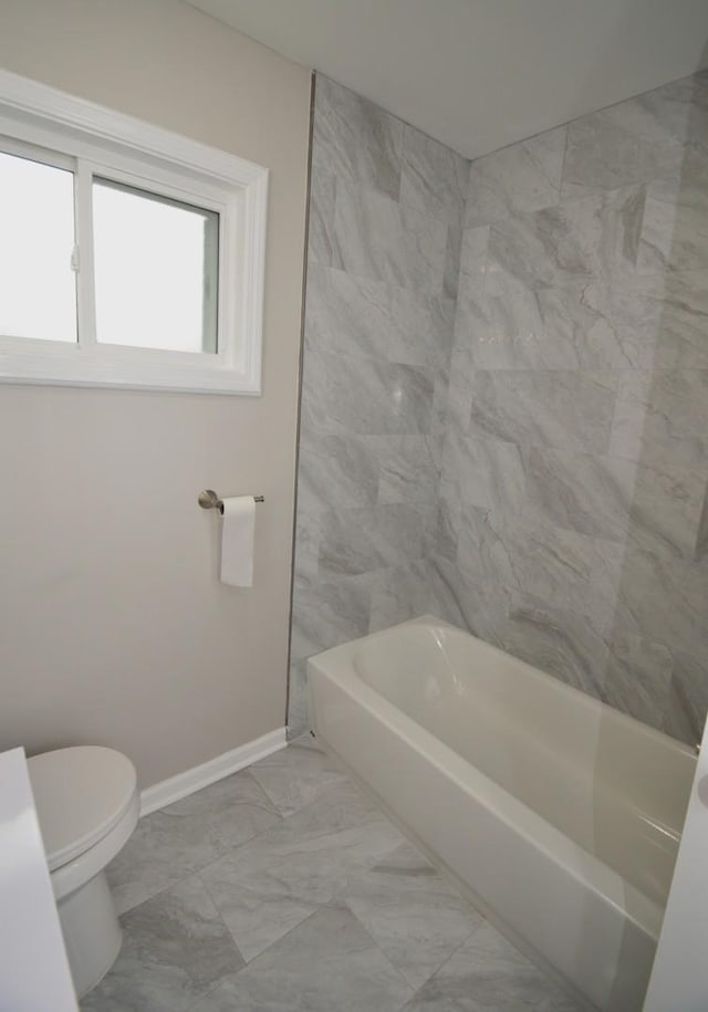 bathroom with tiled shower / bath combo and toilet