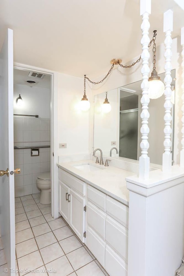 bathroom featuring toilet, vanity, tile patterned floors, and tile walls