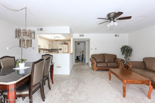 dining space with light carpet and ceiling fan with notable chandelier