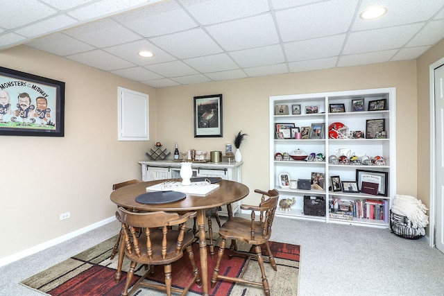 dining room featuring built in shelves, a paneled ceiling, and carpet flooring