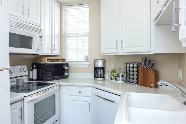 kitchen with white cabinets, plenty of natural light, sink, and white appliances