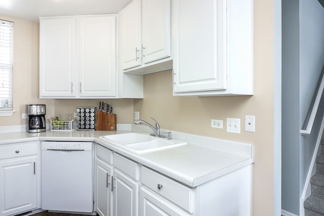 kitchen featuring white dishwasher, sink, and white cabinetry