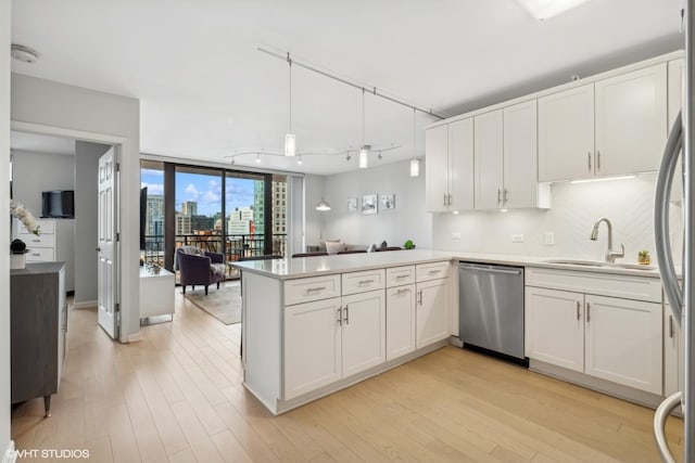 kitchen featuring tasteful backsplash, kitchen peninsula, dishwasher, and white cabinetry