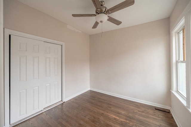 unfurnished bedroom featuring multiple windows, dark hardwood / wood-style floors, and ceiling fan