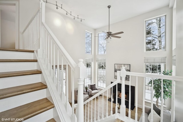 stairway featuring ceiling fan, a towering ceiling, and a wealth of natural light