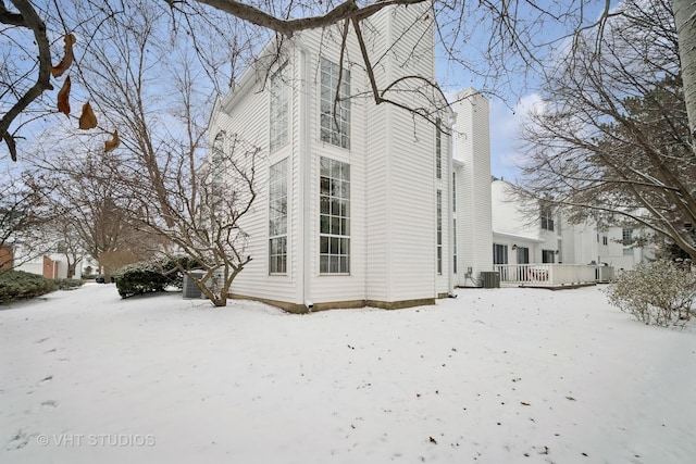 snow covered property with a deck and central AC unit