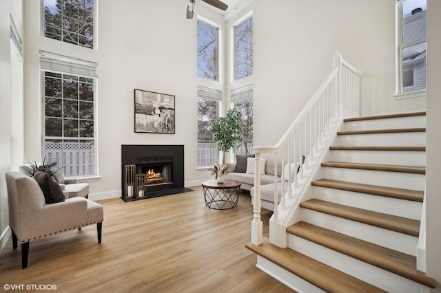 interior space featuring ceiling fan, light hardwood / wood-style floors, and a high ceiling