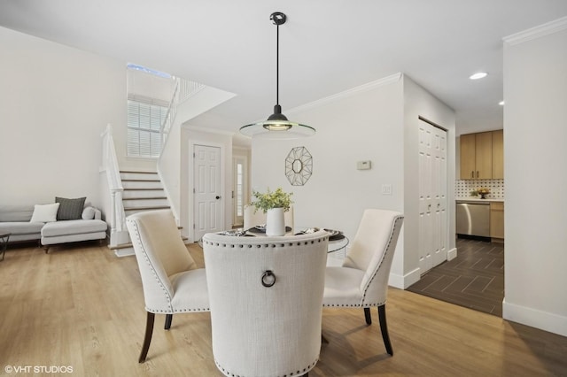 dining area with light wood-type flooring and ornamental molding