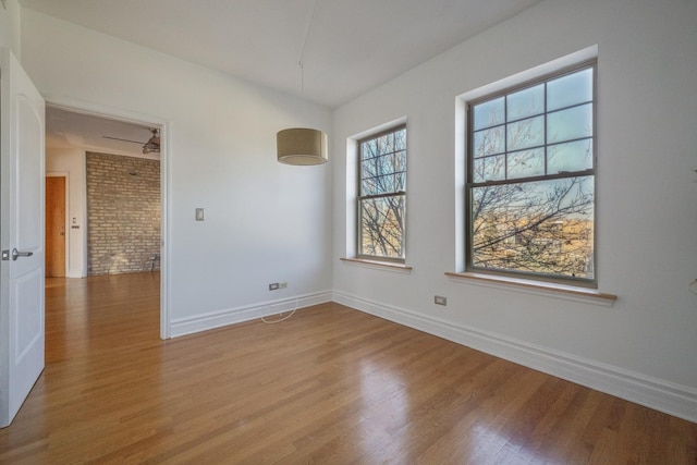 unfurnished room with wood-type flooring and brick wall