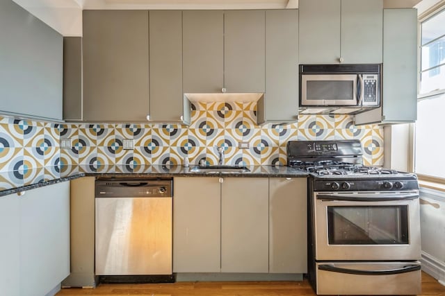 kitchen with dark stone counters, decorative backsplash, sink, and stainless steel appliances