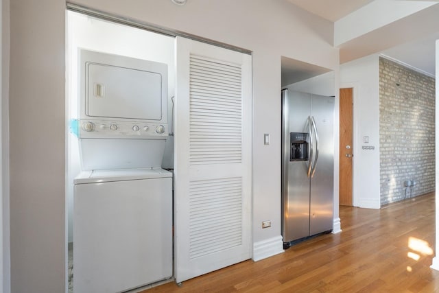 clothes washing area featuring light hardwood / wood-style floors and stacked washer and clothes dryer