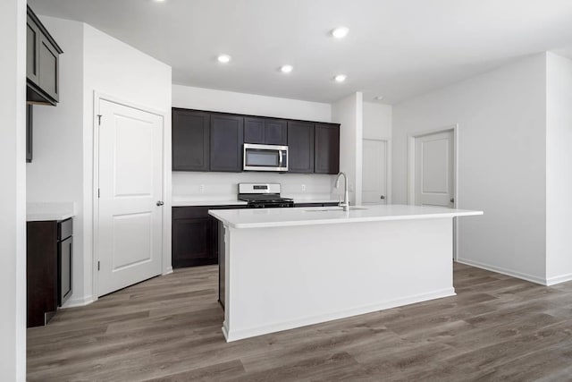 kitchen with a center island with sink, dark hardwood / wood-style flooring, sink, and stainless steel appliances