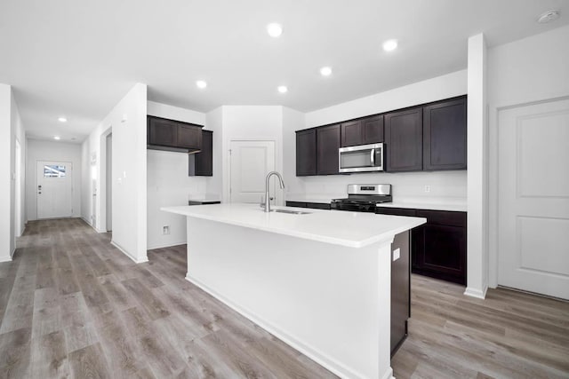 kitchen featuring appliances with stainless steel finishes, an island with sink, light hardwood / wood-style floors, and sink