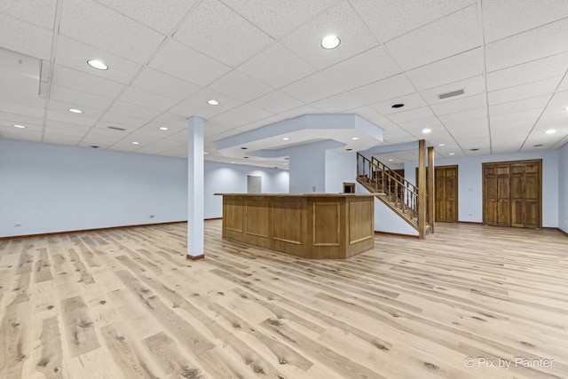 interior space with a paneled ceiling and light hardwood / wood-style flooring