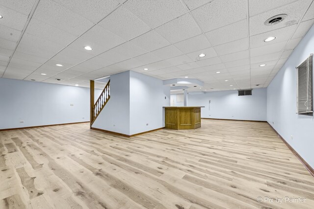 basement featuring a drop ceiling and light wood-type flooring