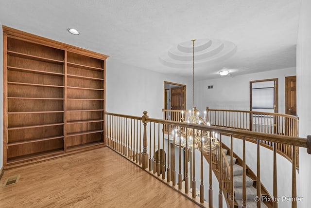 hallway featuring hardwood / wood-style floors and an inviting chandelier