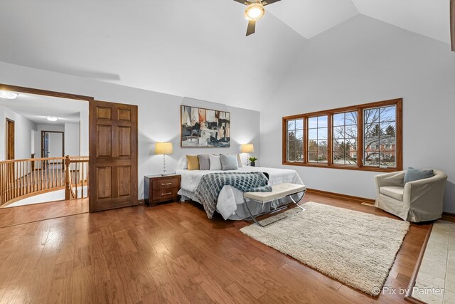 bedroom with hardwood / wood-style floors, high vaulted ceiling, and ceiling fan