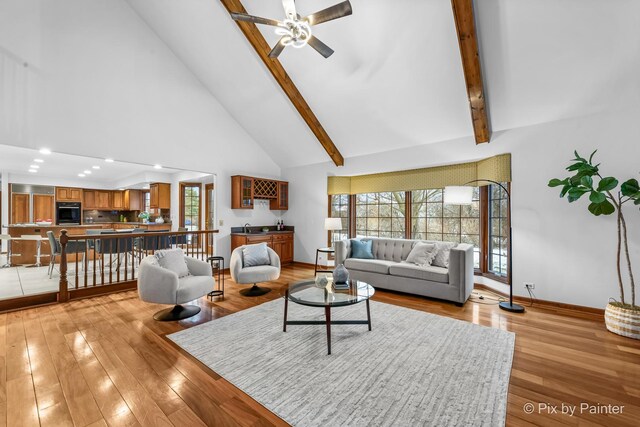 living room with beam ceiling, ceiling fan, high vaulted ceiling, and light hardwood / wood-style floors