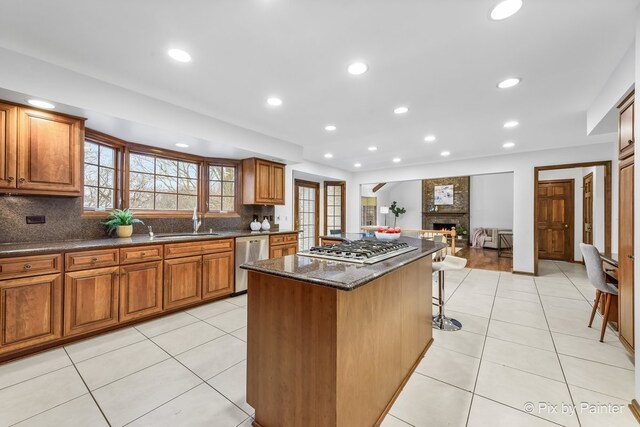 kitchen with a kitchen island, a fireplace, appliances with stainless steel finishes, and tasteful backsplash