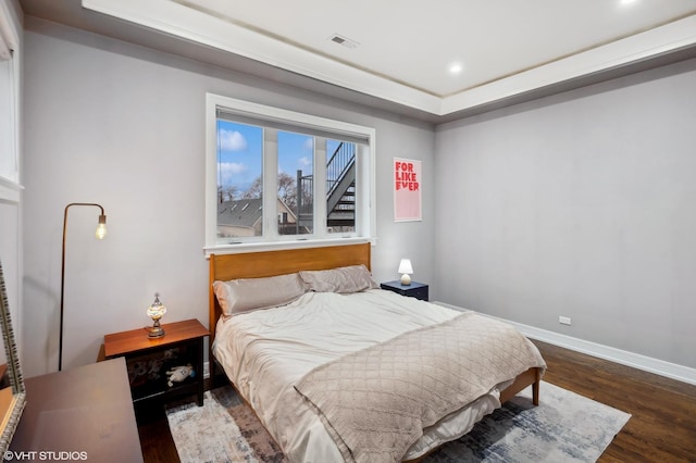 bedroom with a raised ceiling and dark wood-type flooring