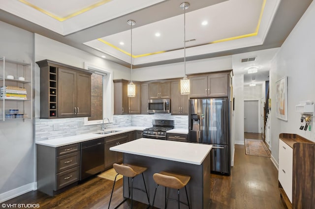 kitchen featuring black appliances, pendant lighting, a raised ceiling, and sink