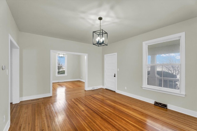 unfurnished dining area with an inviting chandelier and wood-type flooring