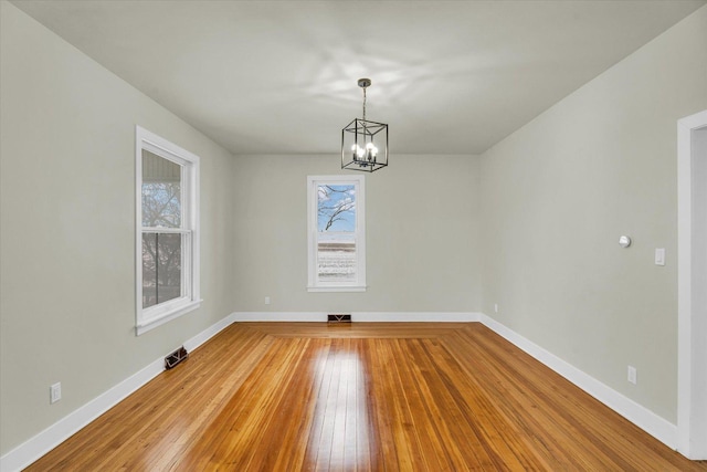 unfurnished dining area with an inviting chandelier and hardwood / wood-style flooring